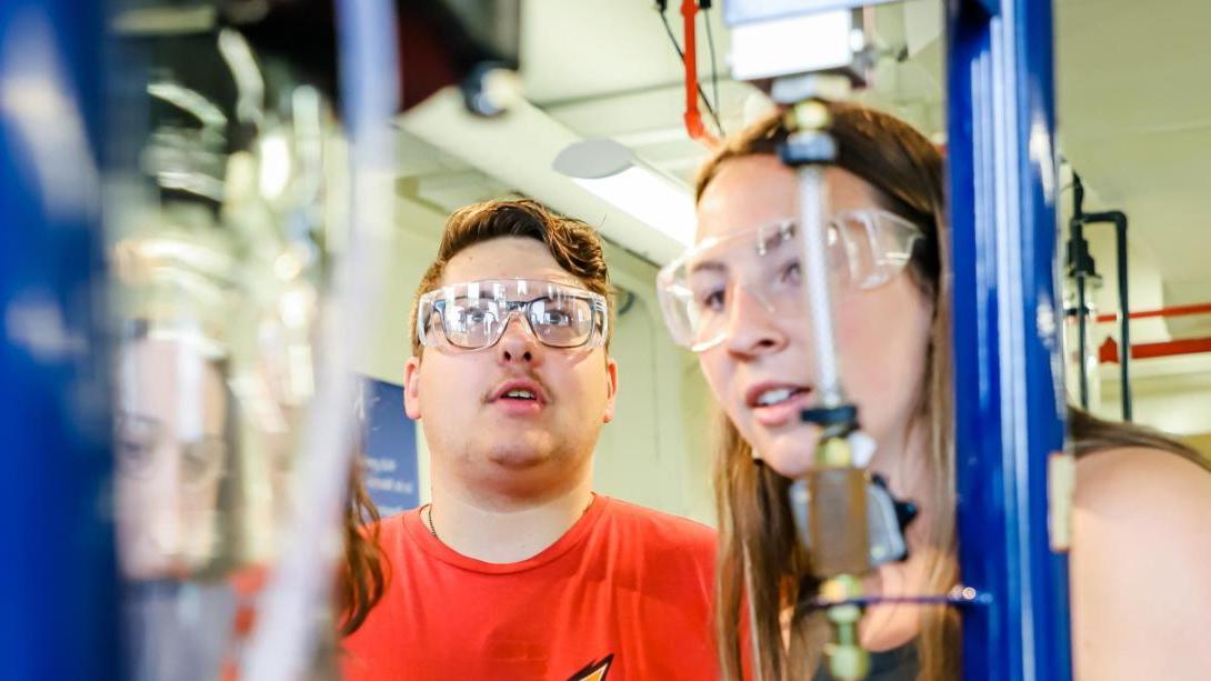 Two Chemical Engineering students in the filtration lab wearing goggles