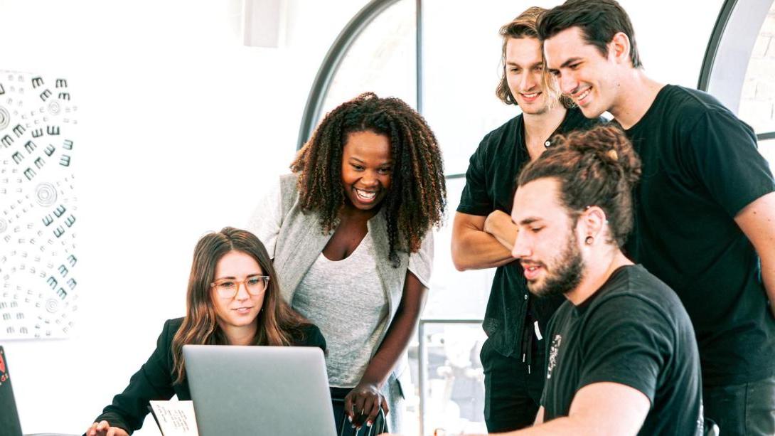 A group of people collaborating around a laptop